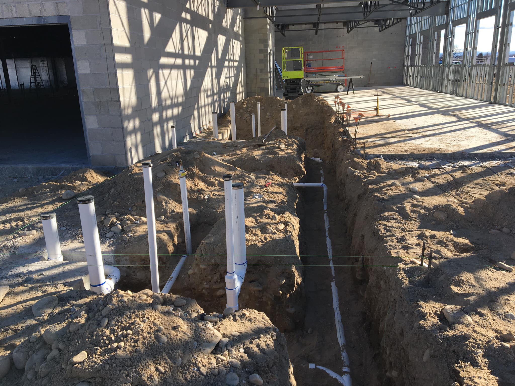 Underground DWV rough-in inside a steel-framed new construction building