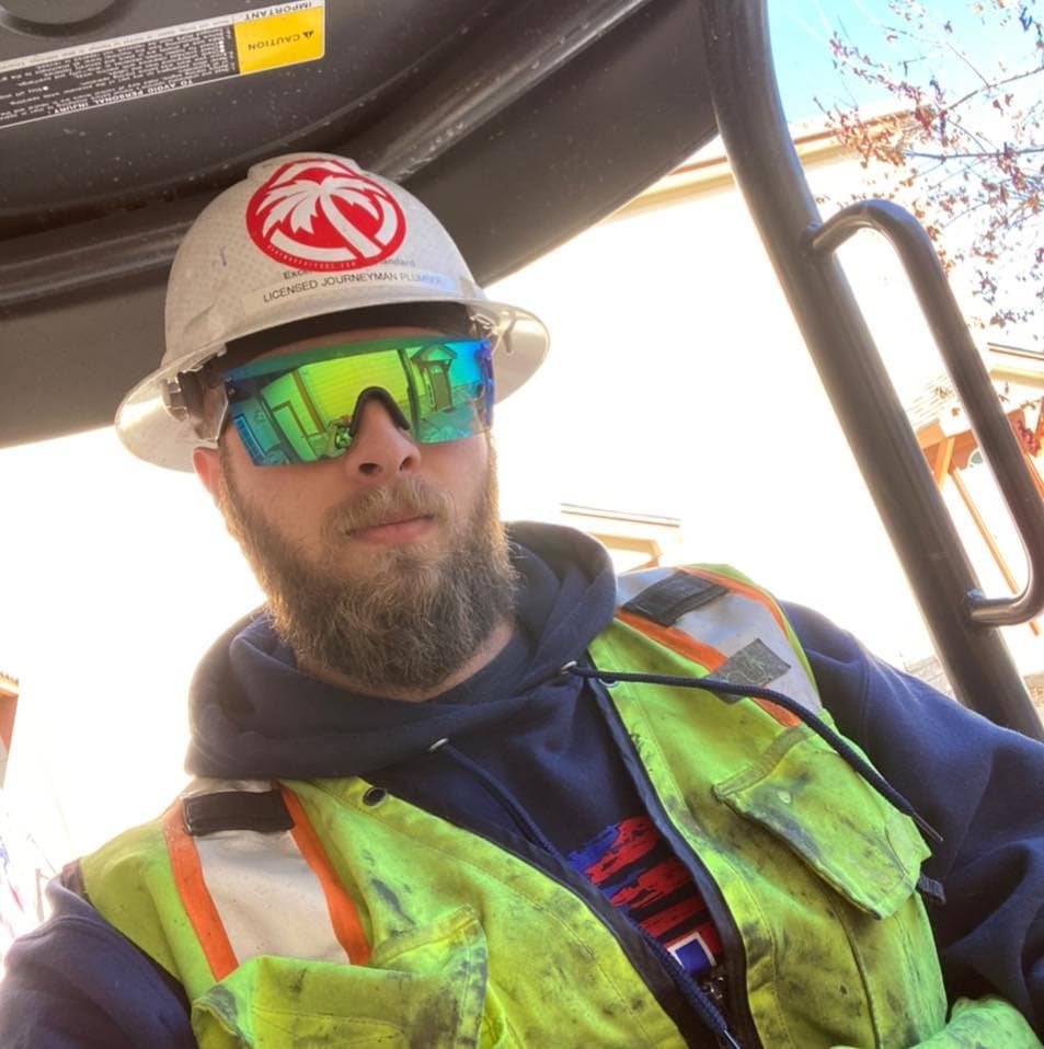Nick Velasquez on-site in a hard hat and hi-vis as a licensed plumber