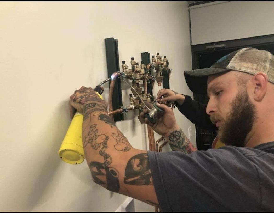 Nick Velasquez soldering a copper manifold during a plumbing rough-in